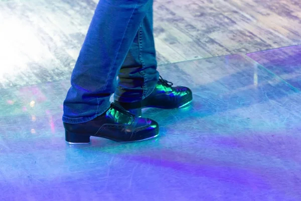 床にアイルランドのダンスのためのストライプや革の靴とステージパンツで動作中の男性の足 床に反射してタップダンスのための黒い作業ブーツ 選択的集中 ステージ上のステップアップ — ストック写真