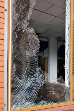 Bomba patlaması sonucu sivil bir binanın camları kırılmış. Cam parçaları pencerenin çerçevesinde tehlikeli bir şekilde duruyor. Ukrayna ve Rusya arasındaki savaş. Patlama ve roket parçalarıyla kırılan sivil pencereler