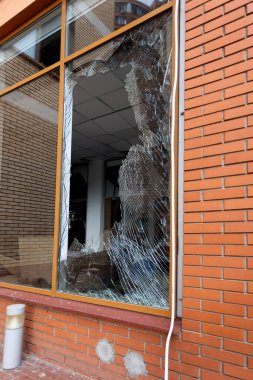 Bomba patlaması sonucu sivil bir binanın camları kırılmış. Cam parçaları pencerenin çerçevesinde tehlikeli bir şekilde duruyor. Ukrayna ve Rusya arasındaki savaş. Patlama ve roket parçalarıyla kırılan sivil pencereler