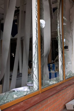 Bomba patlaması sonucu sivil bir binanın camları kırılmış. Cam parçaları pencerenin çerçevesinde tehlikeli bir şekilde duruyor. Ukrayna ve Rusya arasındaki savaş. Patlama ve roket parçalarıyla kırılan sivil pencereler