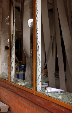 Bomba patlaması sonucu sivil bir binanın camları kırılmış. Cam parçaları pencerenin çerçevesinde tehlikeli bir şekilde duruyor. Ukrayna ve Rusya arasındaki savaş. Patlama ve roket parçalarıyla kırılan sivil pencereler