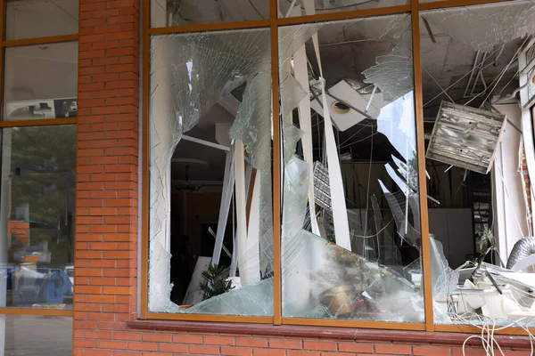 Bomba patlaması sonucu sivil bir binanın camları kırılmış. Cam parçaları pencerenin çerçevesinde tehlikeli bir şekilde duruyor. Ukrayna ve Rusya arasındaki savaş. Patlama ve roket parçalarıyla kırılan sivil pencereler