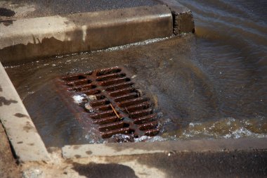 Şiddetli yağmur ve sokak kanalizasyon tıkanma sırasında su akışı. Fırtına kanalizasyon içinde güçlü bir kasırga sırasında su akışı. Yağmur drenaj sistemi boşaltmak için yol boyunca fırtına kanalizasyon