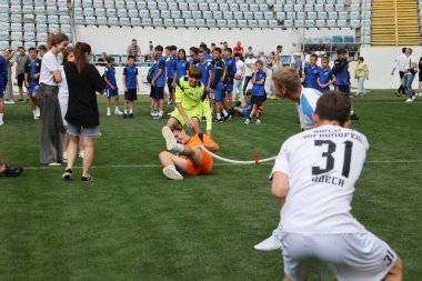 ODESSA, UKRAINE, 9 Haziran 2024: Çocuk takımları spor festivalinde çekişme oyunu oynuyorlar. Spor takımı kavgası. Stadyumun yeşil çimlerinde çekişme. Çocuk sporları. Sağlıklı yaşam tarzı, spor eğlencesi.