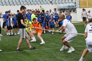 ODESSA, UKRAINE, 9 Haziran 2024: Çocuk takımları spor festivalinde çekişme oyunu oynuyorlar. Spor takımı kavgası. Stadyumun yeşil çimlerinde çekişme. Çocuk sporları. Sağlıklı yaşam tarzı, spor eğlencesi.