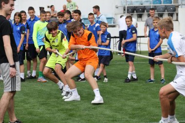 ODESSA, UKRAINE, 9 Haziran 2024: Çocuk takımları spor festivalinde çekişme oyunu oynuyorlar. Spor takımı kavgası. Stadyumun yeşil çimlerinde çekişme. Çocuk sporları. Sağlıklı yaşam tarzı, spor eğlencesi.