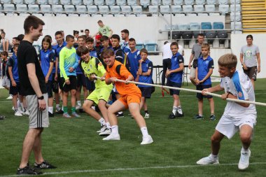 ODESSA, UKRAINE, 9 Haziran 2024: Çocuk takımları spor festivalinde çekişme oyunu oynuyorlar. Spor takımı kavgası. Stadyumun yeşil çimlerinde çekişme. Çocuk sporları. Sağlıklı yaşam tarzı, spor eğlencesi.