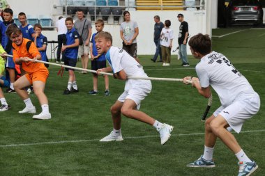 ODESSA, UKRAINE, 9 Haziran 2024: Çocuk takımları spor festivalinde çekişme oyunu oynuyorlar. Spor takımı kavgası. Stadyumun yeşil çimlerinde çekişme. Çocuk sporları. Sağlıklı yaşam tarzı, spor eğlencesi.
