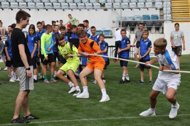 ODESSA, UKRAINE, 9 Haziran 2024: Çocuk takımları spor festivalinde çekişme oyunu oynuyorlar. Spor takımı kavgası. Stadyumun yeşil çimlerinde çekişme. Çocuk sporları. Sağlıklı yaşam tarzı, spor eğlencesi.