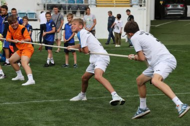 ODESSA, UKRAINE, 9 Haziran 2024: Çocuk takımları spor festivalinde çekişme oyunu oynuyorlar. Spor takımı kavgası. Stadyumun yeşil çimlerinde çekişme. Çocuk sporları. Sağlıklı yaşam tarzı, spor eğlencesi.