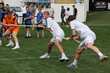 ODESSA, UKRAINE, 9 Haziran 2024: Çocuk takımları spor festivalinde çekişme oyunu oynuyorlar. Spor takımı kavgası. Stadyumun yeşil çimlerinde çekişme. Çocuk sporları. Sağlıklı yaşam tarzı, spor eğlencesi.