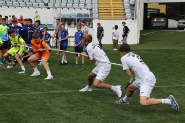 ODESSA, UKRAINE, 9 Haziran 2024: Çocuk takımları spor festivalinde çekişme oyunu oynuyorlar. Spor takımı kavgası. Stadyumun yeşil çimlerinde çekişme. Çocuk sporları. Sağlıklı yaşam tarzı, spor eğlencesi.