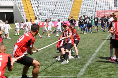 ODESSA, UKRAINE, 9 Haziran 2024: Çocuk takımları spor festivalinde çekişme oyunu oynuyorlar. Spor takımı kavgası. Stadyumun yeşil çimlerinde çekişme. Çocuk sporları. Sağlıklı yaşam tarzı, spor eğlencesi.