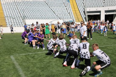 ODESSA, UKRAINE, 9 Haziran 2024: Çocuk takımları spor festivalinde çekişme oyunu oynuyorlar. Spor takımı kavgası. Stadyumun yeşil çimlerinde çekişme. Çocuk sporları. Sağlıklı yaşam tarzı, spor eğlencesi.