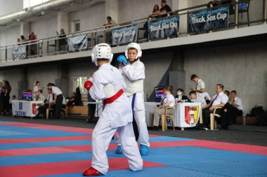 ODESSA, UKRAINE - 21 Eylül 2024: Çocuk ve gençlik sporları. Çocuklar ve kızlar tatami çocuk sporlarında karate dövüşü yapar. Sağlıklı bir yaşam tarzı. Karate sporu yapan çocuklar. Karatekalarla savaş