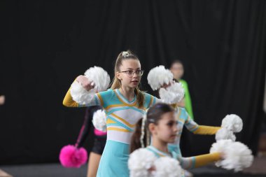 ODESSA, UKRAINE - 30 Nisan 2025: Çocuk Amigoluğu Şampiyonası. Genç ponpon kızlar spor salonundaki şehir ponpon kız şampiyonasında gösteri yapıyorlar. Çocuk sporları, sağlıklı yaşam tarzı. Seyirciler, duygular