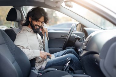 Kıvırcık saçlı genç bir ortadoğulu iki eliyle arka planda tutarak acı ya da rahatsızlık gösteriyor. İfadesi acı veriyor..