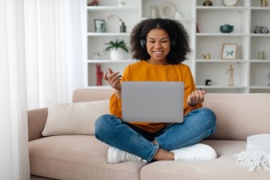 Kulaklıklı Afro kız evde dizüstü bilgisayar kullanıyor Skype konferansı yapıyor, boş yer var. Yüksek kalite fotoğraf
