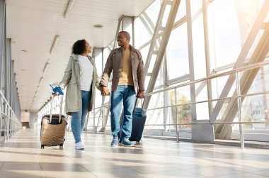 Havaalanı Terminali 'nde yürüyen, uçuştan önce dinlenen mutlu Afrikalı Amerikalı çift. Yüksek kalite fotoğraf