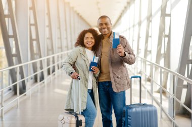 Havaalanında uçuş biletleri ve pasaportlarıyla gülümseyen sevimli Afrikalı çift. Yüksek kalite fotoğraf