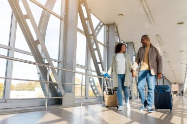 Tatil gezisi. Romantik Afrikalı çift bavullarıyla havaalanının kapısına yürüyorlar, bavullarla yürüyorlar ve kucaklaşıyorlar, boş alan. Yüksek kalite fotoğraf