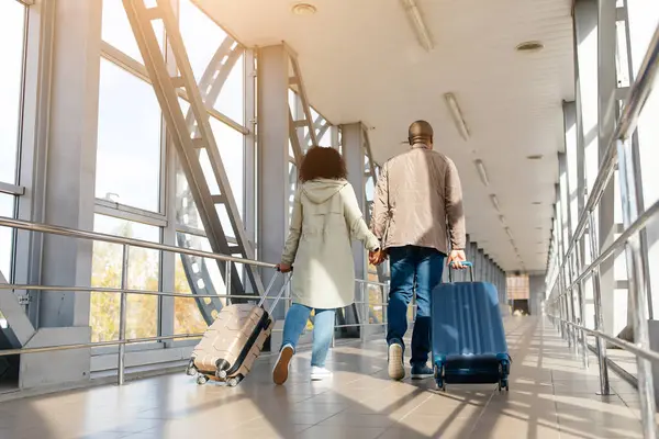 Afro-Amerikan erkek ve kadını sevmek havaalanı terminalinde bavullarla, boş alanla yürümek. Yüksek kalite fotoğraf