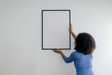 Beyaz Duvar Dekorasyon Evi 'nde asılı duran Esmer Kadın Boş Resim. Modern sanat ve ev dekorasyonu. Boş Poster 'e Odaklan. Modelleme. Yüksek kalite fotoğraf