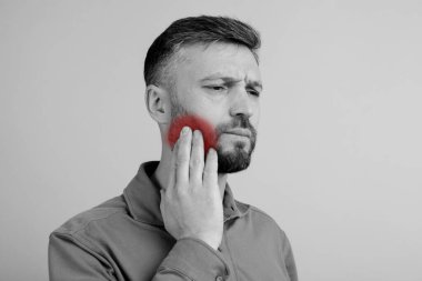 Diş problemi. Güçlü diş ağrısı çeken bir adam, gri arka plan, fotokopi odası. Yanağını ovuşturan orta yaşlı bir adam, diş iltihabı, pulpitis ya da diş bakımı var. Yüksek kalite fotoğraf