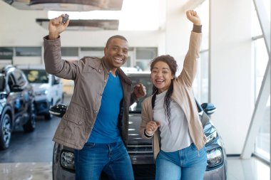 Yeni araba. Heyecanlı Afrikalı Eşler Otomobil Otomobil Mağazasında Yeni Aile Otomobili Yakınındaki Sarsıntılı Yumrukları Kutluyor. Yüksek kalite fotoğraf
