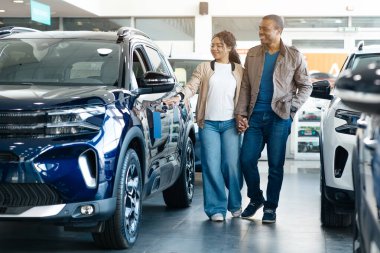 Otomobil galerisindeki lüks aracın yanında birlikte duran yeni arabayı seçen çift. Aile arabası konsepti. Panorama, Serbest Alan. Yüksek kalite fotoğraf