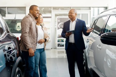 Araba galerisi. Otomobil galerisindeki müşterilere Neşeli Menajer Otomobil Gösteriyor. Uzayı kopyala Yüksek kalite fotoğraf