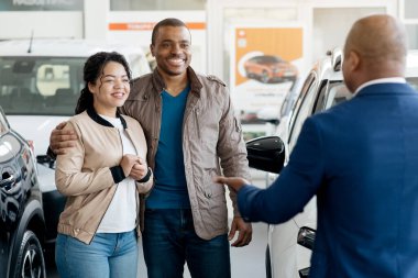 Araba satışı işi. Afro-Çift Alıcılarıyla konuşup galeride Oto-Standing satıyorlar. Seçici Odaklanma. Yüksek kalite fotoğraf