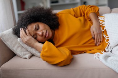 Kendimi iyi hissetmiyorum. Sağlıksız, hasta, siyah bir kadın, gündelik kıyafetlerle evdeki kanepede uzanıyor, baş ve karnına dokunuyor, regl sırasında acı çekiyor, baş ağrısı çekiyor ve adet sancısı çekiyor.