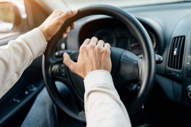 Araba sürerken korna çalan, arabada oturan genç adama yakın çekim. Direksiyona seçici odaklanma, otomatik olarak kornaya basan tanınmayan sürücü. Ulaşım ve trafik kavramı