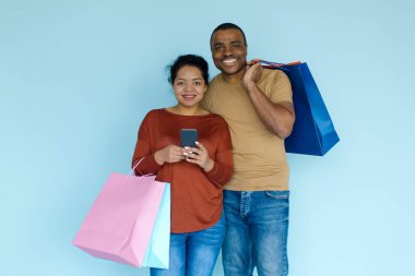 İndirimli uygulama. Neşeli Siyah Çift Akıllı Telefon ve Renkli Kağıt Alışveriş Torbaları, Afro-Amerikan Eşleri Mobil Mobil Uygulama Kuponları, Promosyon Kodları ve Mavi Arkaplan Üzerinde Anlaşmalar