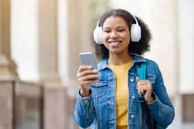 Parlak tebessümle yürüyen, elinde telefonuyla beyaz kulaklık takan, akıllı telefonuyla mesajlaşan ya da kampüste müzik dinleyen Afro-Amerikan genç bir kız öğrenci.