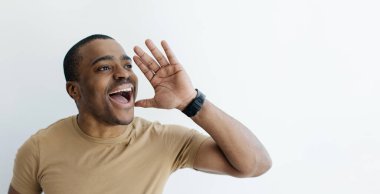 Heyecanlı, eli ağızda olan genç siyah adam, Beyaz Stüdyo Arkaplanı, Panorama, Kopyalama Alanı 'nda dururken Afro-Amerikan Erkek Paylaşımı Haberleri ya da Bilgileri Duyuruyor