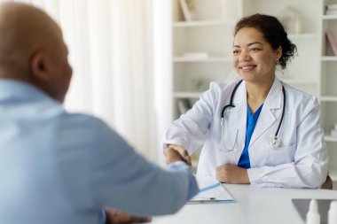 Tıbbi Destek Konsepti. Doktor Kadın ve Siyah Hasta Toplantısı sırasında el sıkışıyor, Beyaz Ceketli Gülümseyen Kadın Terapist, Ofisinde Olgun Afro-Amerikan Adamı Karşılıyor,