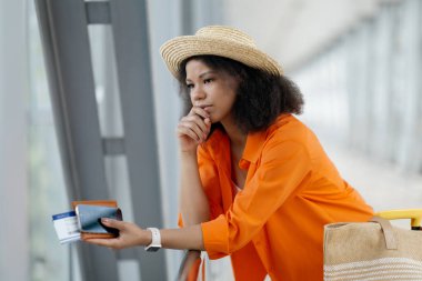 Uçuş İptal Sorunu. Havalimanında bekleyen mutsuz siyahi kadın, pasaport ve akıllı telefonlu Afro-Amerikan kadını elinde parmaklıklara yaslanmış, yakın çekim