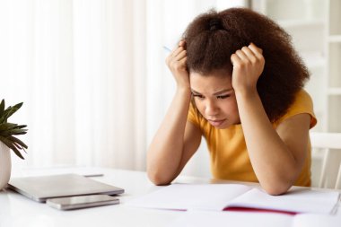 Stresli genç siyahi kadın dizüstü bilgisayarı ile masada oturuyor ve kafasına dokunuyor, Afro-Amerikan kadın hayal kırıklığıyla dizüstü bilgisayarına yaslanıyor, evde tek başına çalışmaktan duygusal yorgunluk çekiyor.