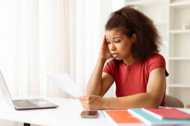 Evrakları tutan ve alnına dokunan, hayal kırıklığına uğramış genç siyahi kadın, çalışırken ya da ev ofisinden uzaktan çalışırken bunalmış hissediyor, boşluğu kopyalıyor