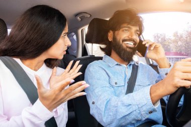 Hüsrana uğramış Hintli kadın, araba sürerken telefonla konuşurken el kol hareketi yapıyor. Dikkat dağınıklığı, ilişki gerilimi, güvensiz sürüş ve günlük hayatta çiftler arası çatışma, yakın çekim