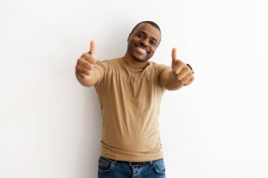 Gülümseyen siyah adam, neşeli ve kendine güvenen duruşuyla iki kez baş parmak kaldırıyor. Tesadüfi ve dostane bağlamda olumlu onay ya da teşvik, kopyalama alanı