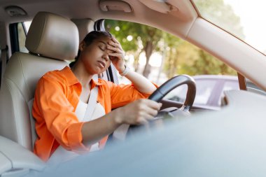 Yorgun genç siyahi kadın arabada kafa kafaya dinleniyor. Belli ki boğulmuş ya da duygusal olarak tükenmiş, muhtemelen uzun ve stresli bir günün ardından, yakın çekim.