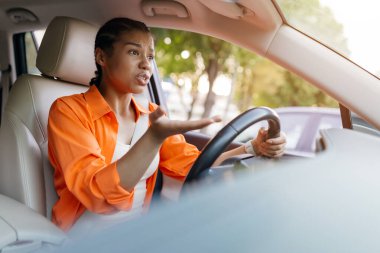 Hüsrana uğramış siyahi kadın araba sürerken konuşuyor, el kol hareketi yapıyor. Afro-Amerikan kadın sinirli görünüyor, yolda üzücü bir şeye tepki veriyor, yakın plan.