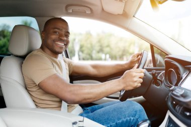 Mutlu siyah adam araba sürüyor ve gülümsüyor, Afro-Amerikan erkeği güneşli bir günde keyifli bir yolculuk sırasında pozitif enerji ve zevk gösteriyor, yakın çekim.