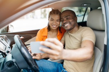 Gülümseyen siyah çift arabalarının içinde selfie çekiyorlar, Afrikalı Amerikalı eşler yolculuklarının eğlenceli anılarını yakalıyorlar, yakın çekimler yapıyorlar.