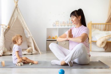 Bebek yakınlarda oynarken anne evde yoga yapıyor. Yaşam tarzı aile dengesi, annelik aşkı, çocuk bakımı, egzersiz, rahatlama ve birbirine bağlanma kavramı