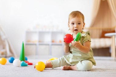 Halıda oyuncak tutan, renkleri ve şekilleri keşfeden sevimli bir kız bebek. Çocukluk hayatı, evde neşe, merak, erken öğrenme, aşk ve aile bakımı ile geçer.