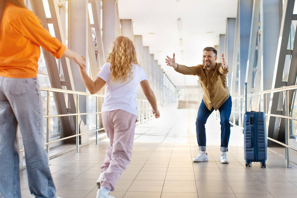 Радостный кавказский отец приветствует дочь с распростертыми объятиями в аэропорту после прибытия, показывая связь, образ жизни и счастливый момент воссоединения семьи путешествия